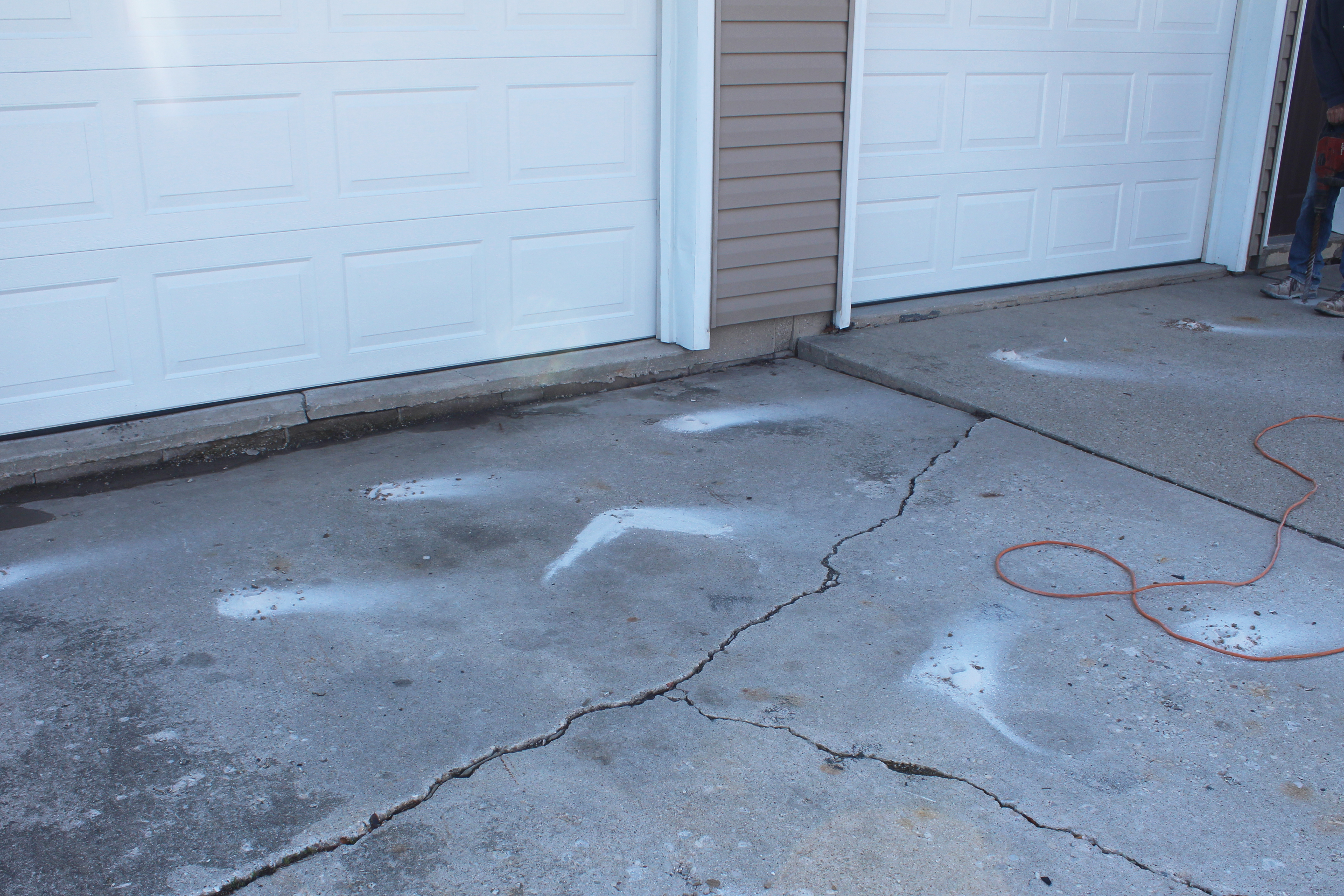 Cracked concrete driveway in Houston Texas with water damage and pooling showing drainage grade problems from slab settlement